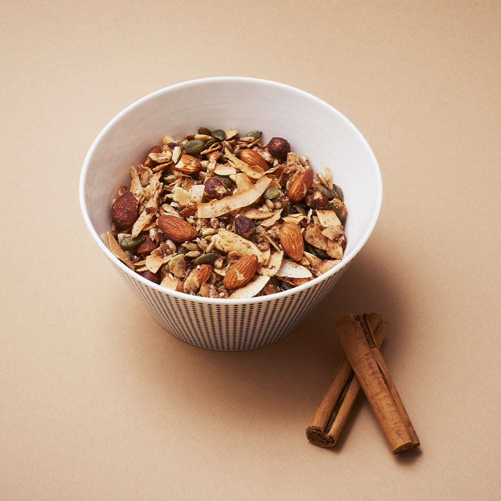 a bowl of keto hana cinnamon keto granola with sticks of cinnamon by the bowl