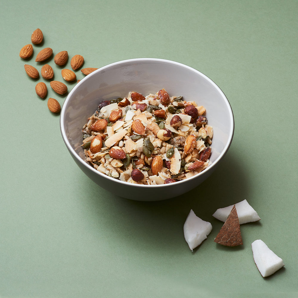 a bowl of keto hana coconut and almond keto granola with coconut pieces and almonds by the bowl