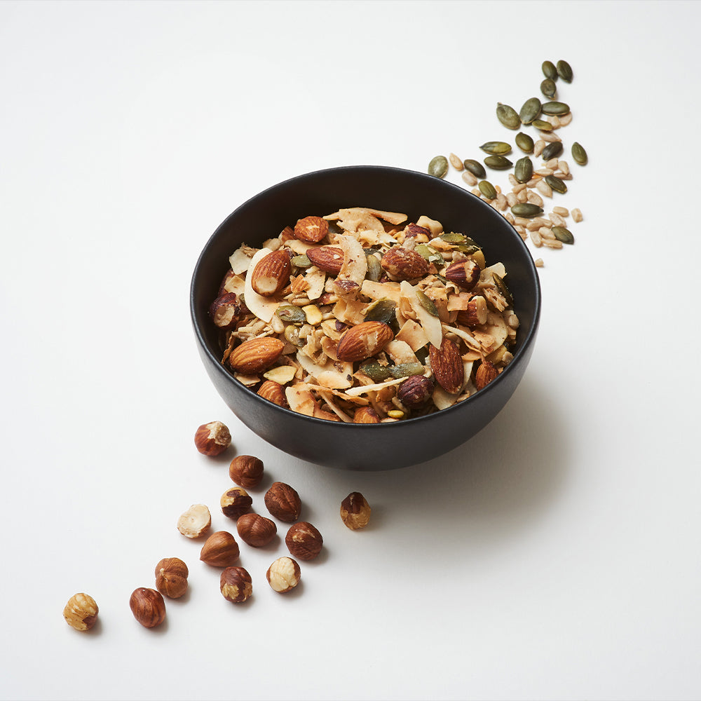 a bowl of keto hana keto granola with nuts and pumpkin seeds by the bowl
